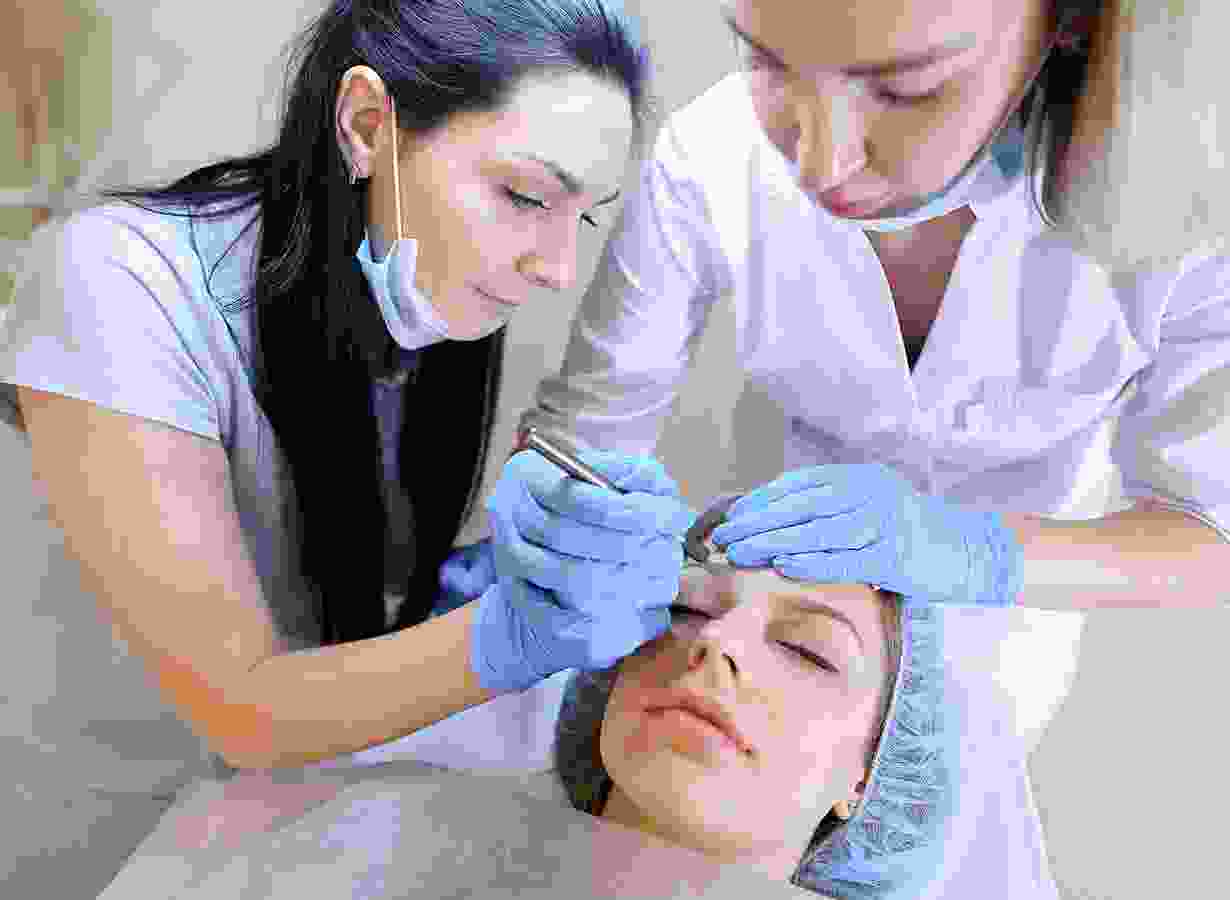 A woman is getting her face waxed by two other women.